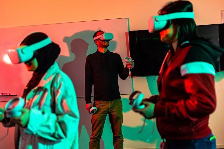 A professor and researcher and his students wear virtual reality headsets in a classroom.