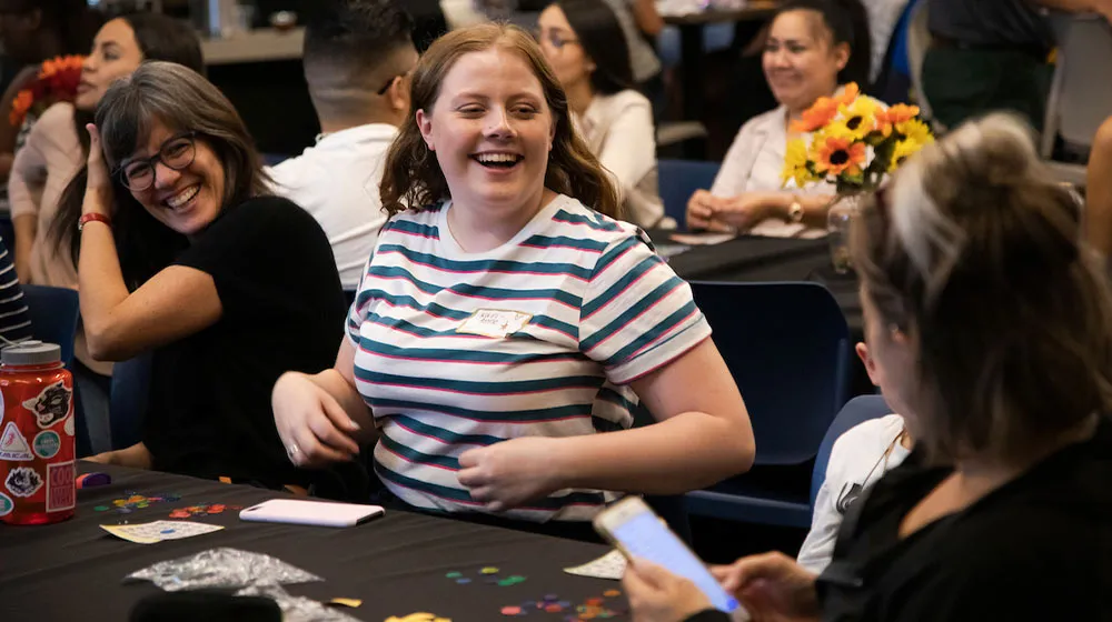 Students laughing and talking together at a table during a group activity.