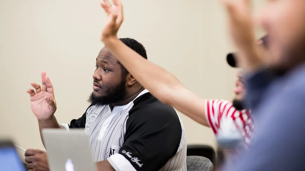 Students with hands raised during an interactive classroom discussion.