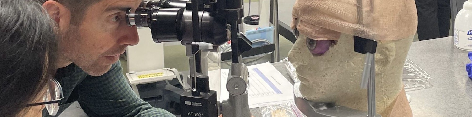 Professor and student viewing eye model through slit lamp
