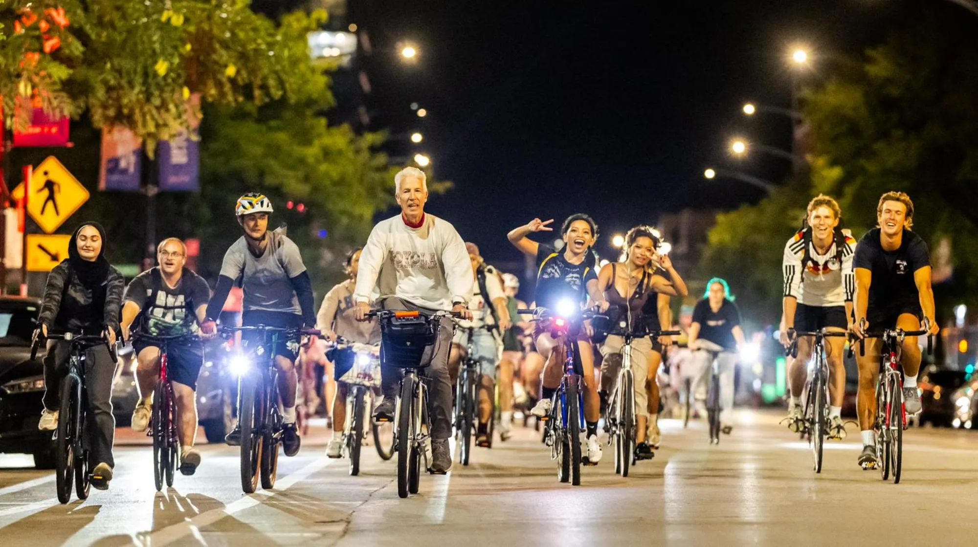 Group of people riding bicycles together on a city street at night