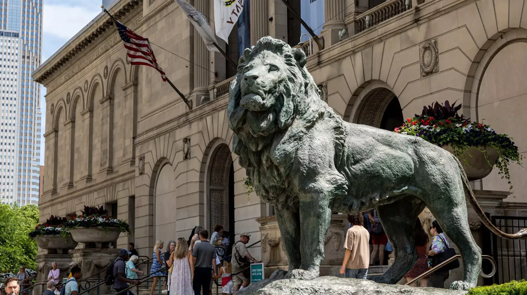 Bronze lion statue outside a historic building with people entering