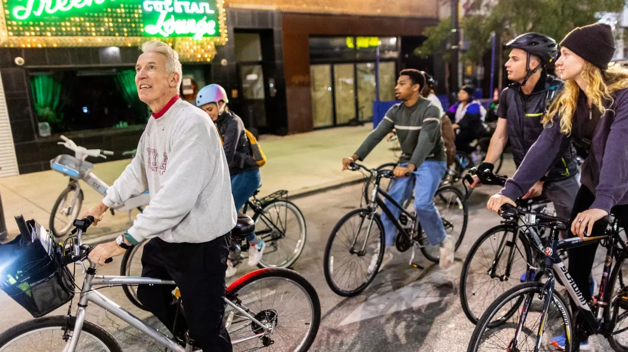 Group of people riding bicycles together on a city street at night