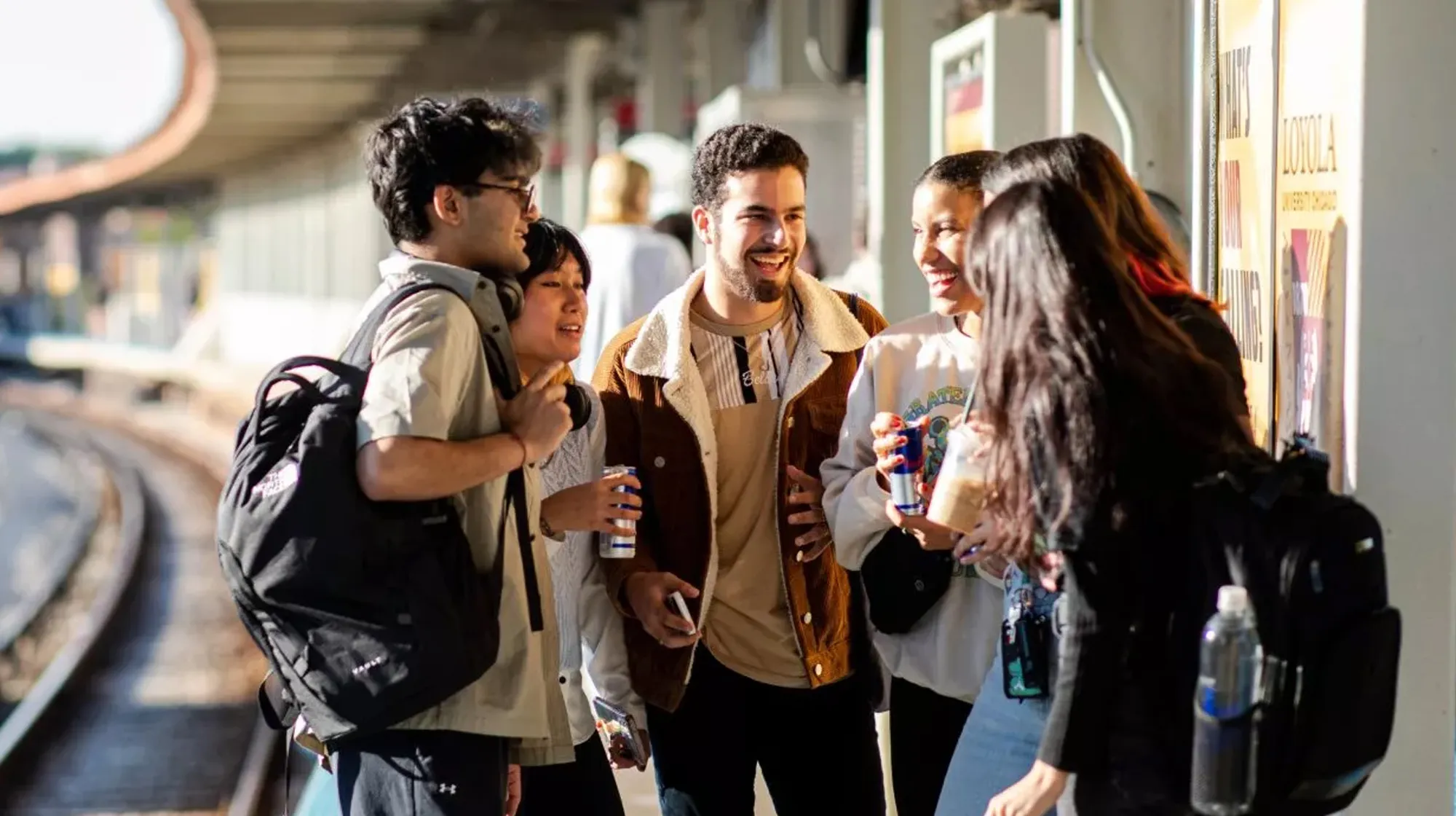 Group of students talking and laughing together on a train platform
