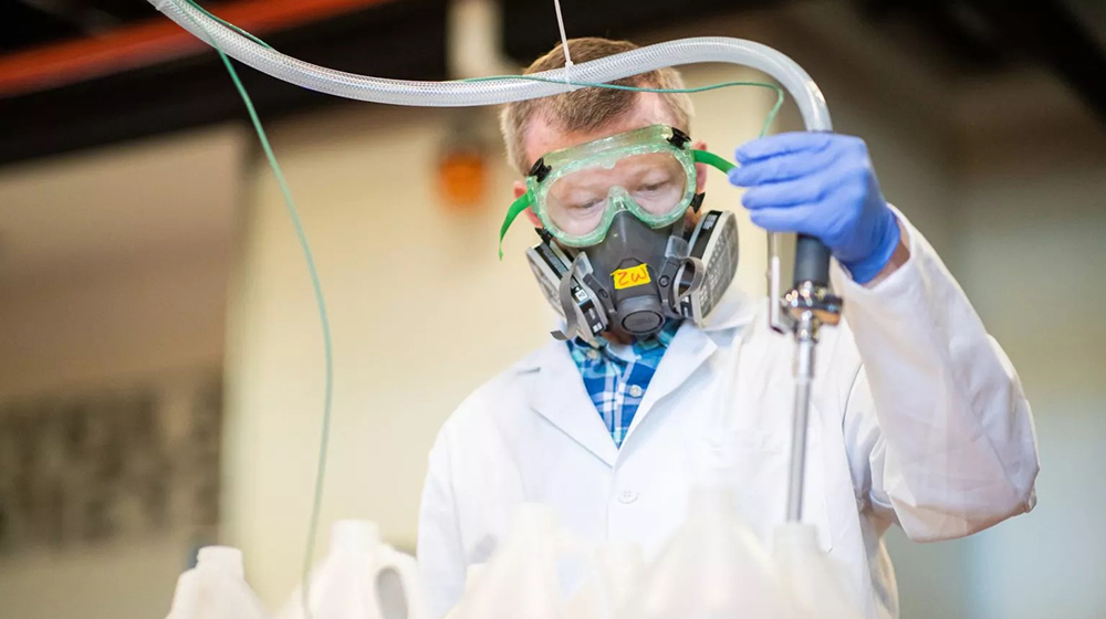 Zach Waickman, lab manager in the Searle Biodiesel Lab, fills gallons with hand sanitizer.