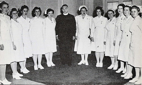 Rev. George Warth, S.J., and Capt. Sara Abrams stand with Loyola nurses of the 108th General Hospital unit