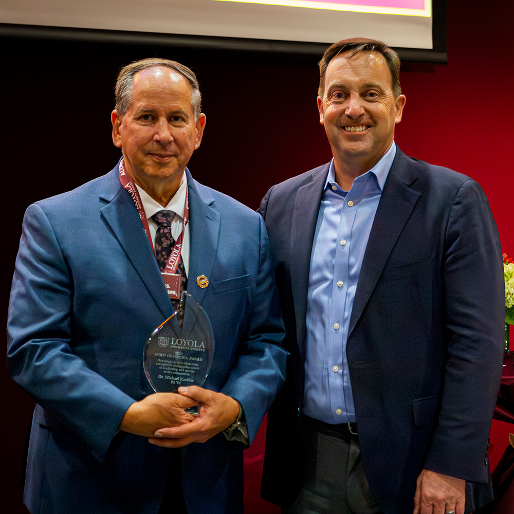 Dr Michael Koehler (BS 82) accept the 2025 Spirit of Loyola Award from Dr Reed.