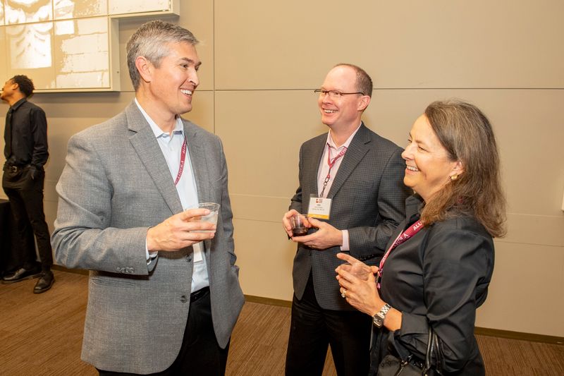 Three Loyola alumni socialize over drinks at a Loyola networking event.