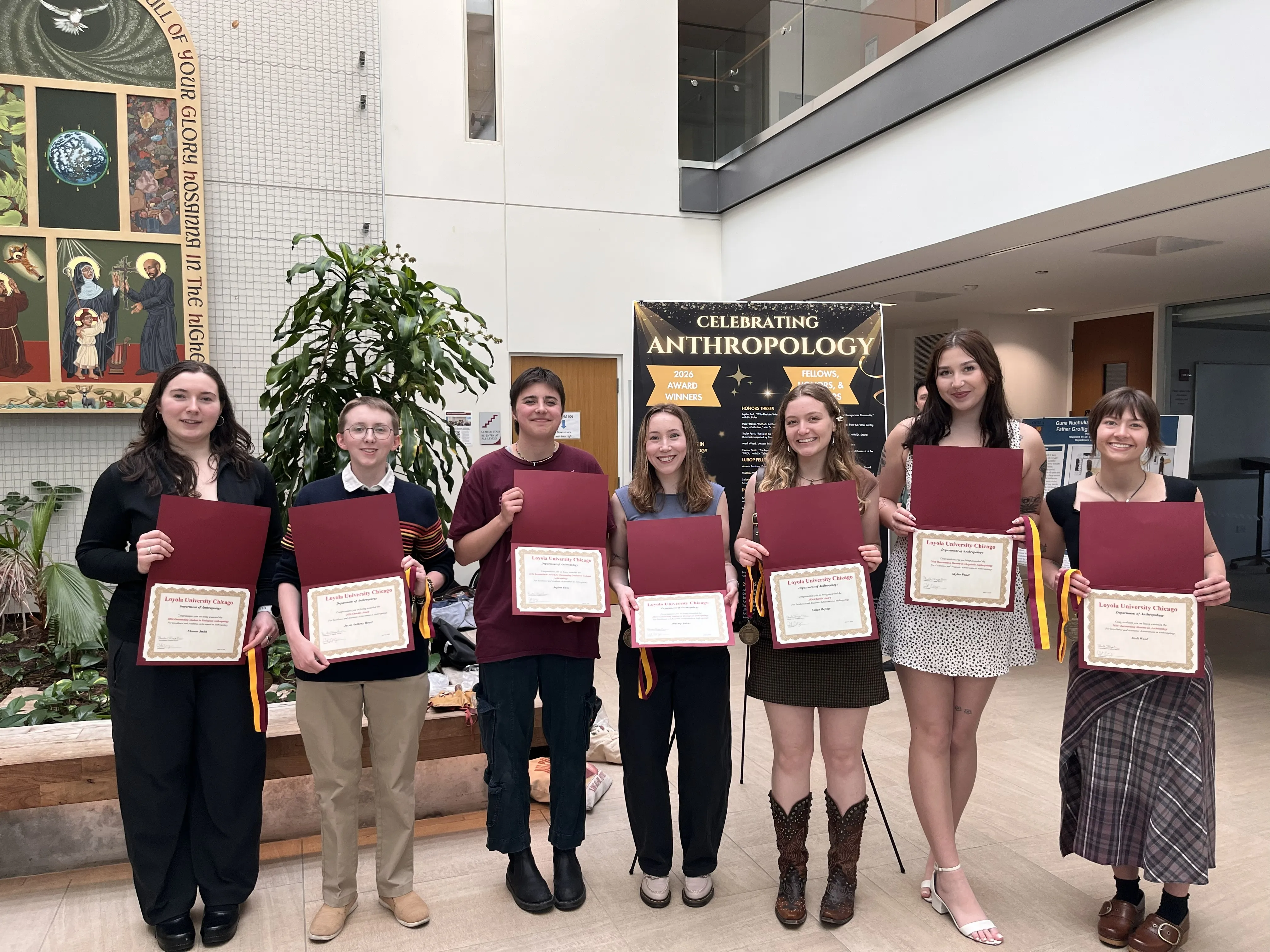 A group of students standing while smiling and holding their awards