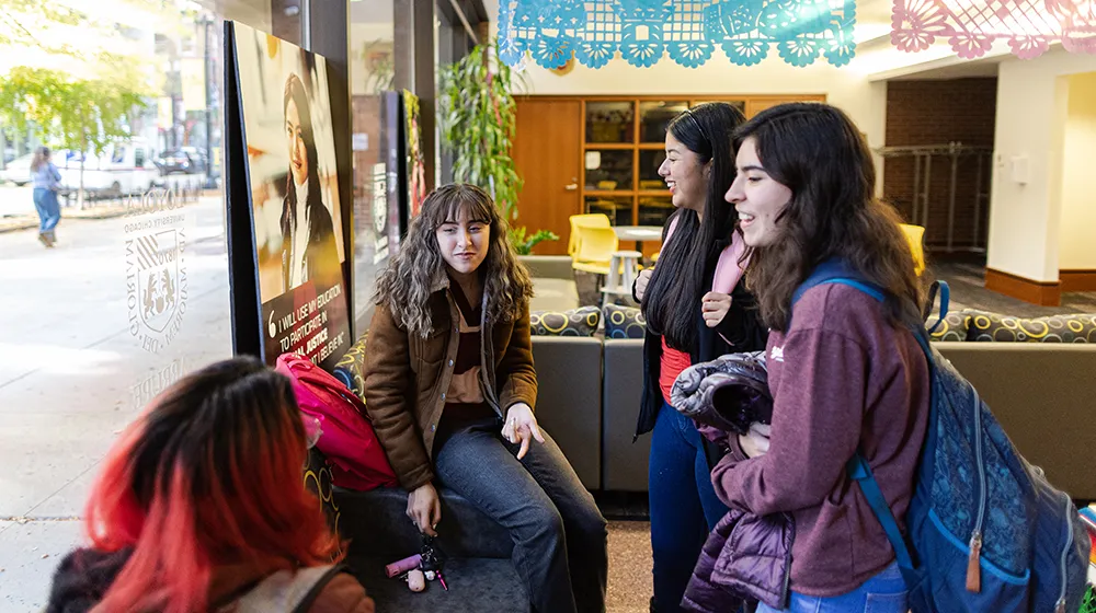 Students gathered in a campus common area, talking and smiling beneath text promoting student life and opportunities at Arrupe College.
