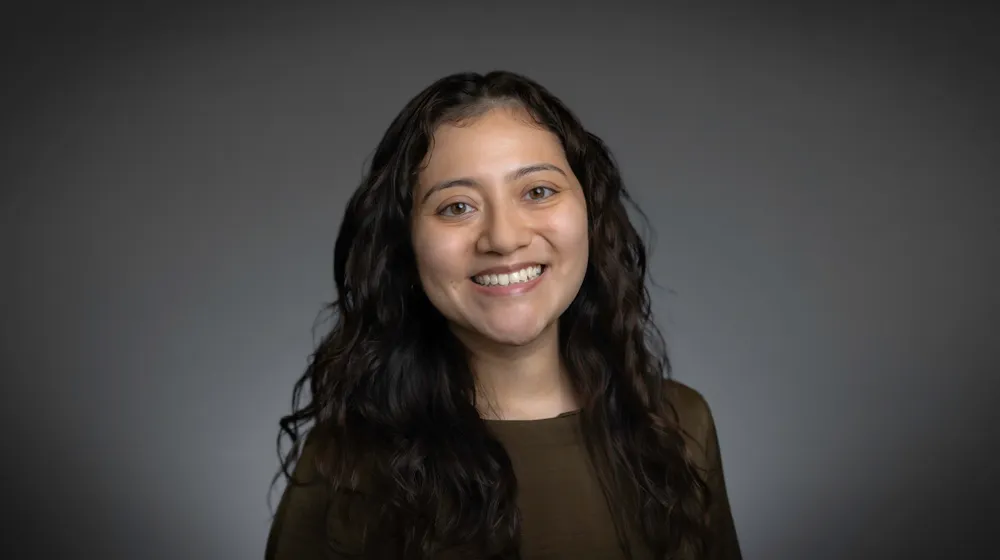 Portrait of a smiling woman with long dark wavy hair against a gray background. Portrait of a smiling woman with long dark wavy hair against a gray background.