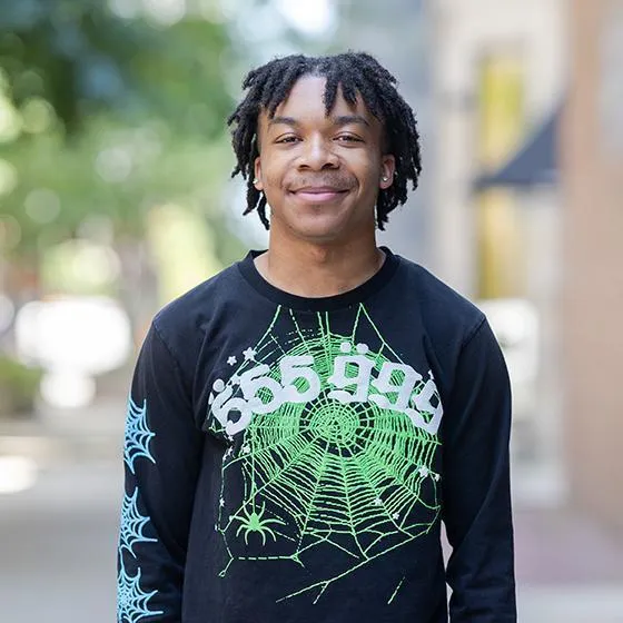 Portrait of a smiling student wearing a black graphic sweatshirt on Loyola University Chicago’s campus.