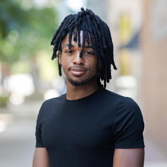 Portrait of a student standing outdoors on Loyola University Chicago’s campus with trees and buildings in the background. Portrait of a student standing outdoors on Loyola University Chicago’s campus with trees and buildings in the background.