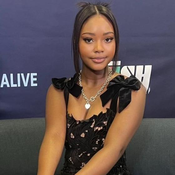 Portrait of a student in a black formal dress seated at an event, smiling toward the camera. Portrait of a student in a black formal dress seated at an event, smiling toward the camera.