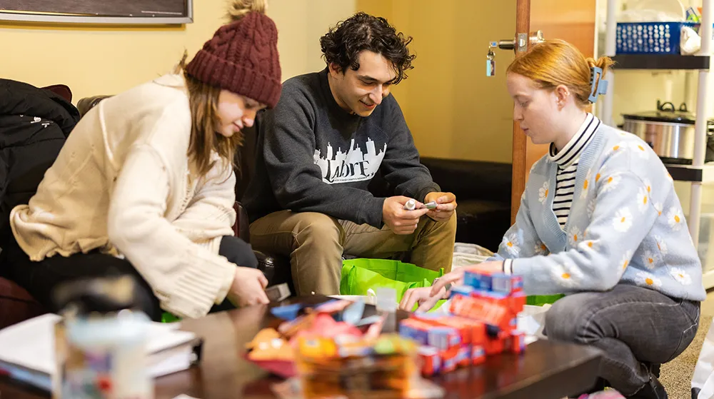 Three students preparing personal hygiene bags for Labre Homeless Ministry