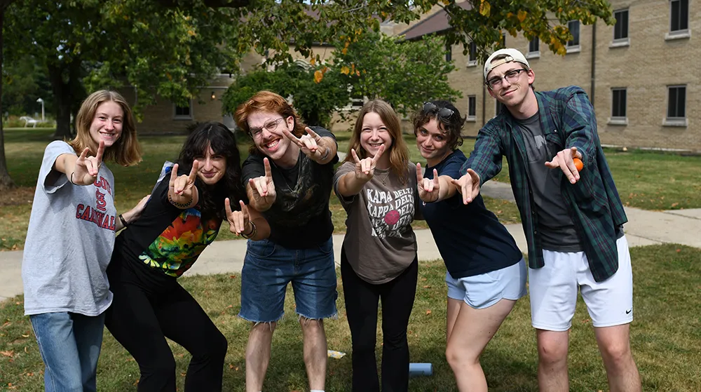 Six students making the Loyola Rambler with their hands, smiling