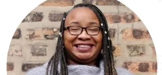 Westinghouse College Prep High School teacher Nina Hike, wearing glasses and smiling in front of a brick wall.