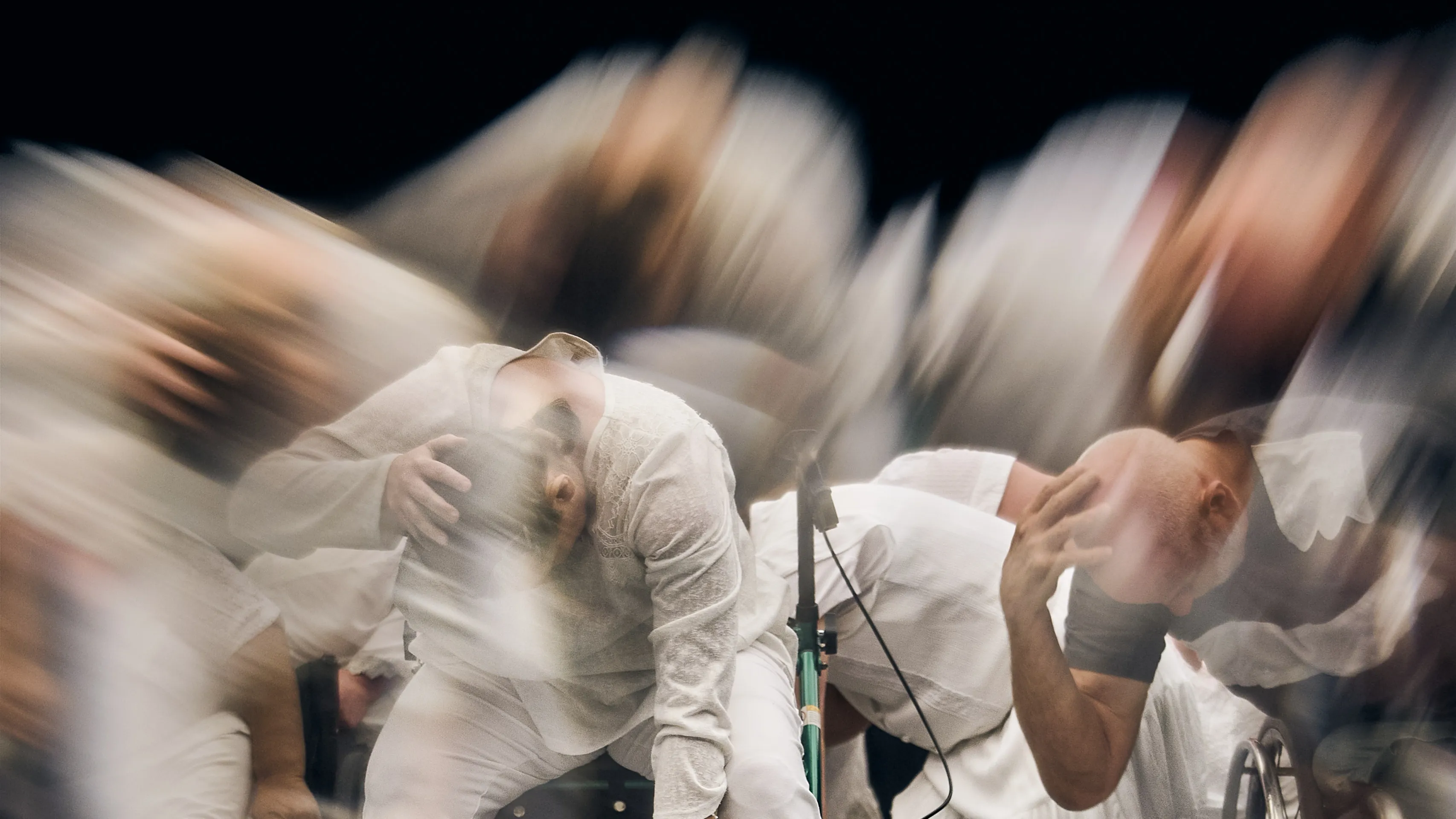 Group of dancers leaning down with their heads in their hands performing And Yet We Are Here Group of dancers leaning down with their heads in their hands performing And Yet We Are Here