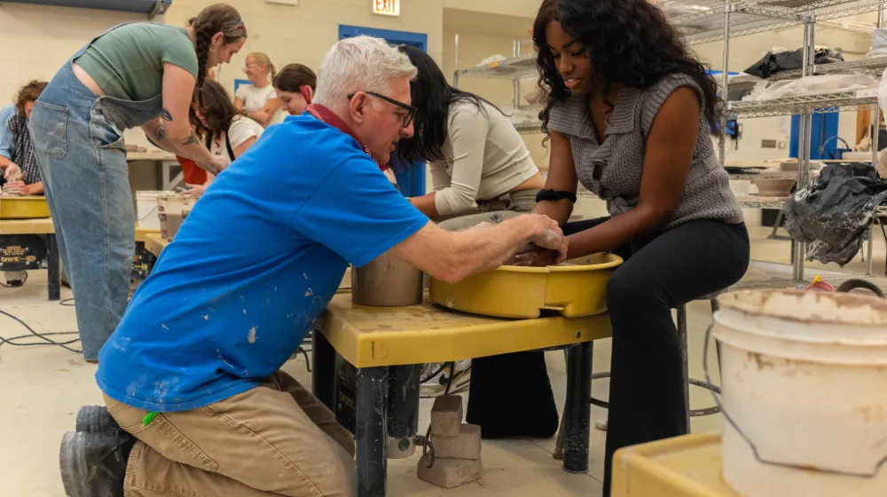 Мэттью Гровс помогает студенту в керамической студии