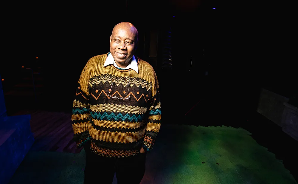 ロヨラ大学シカゴ校劇場のバックステージで、模様入りのセーターを着て笑うジョナサン・ウィルソン