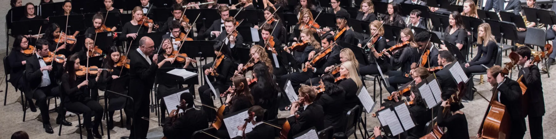 Director of Symphony Orchestra, Colin Holman leads student orchestra onstage