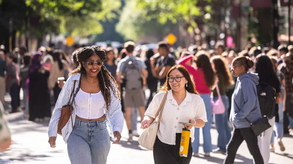 Two students walk down a sunny street during a block party.