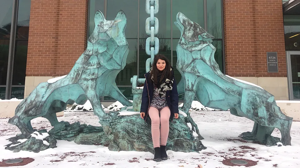 A student seated by the teal wolf statues on Loyola's campus
