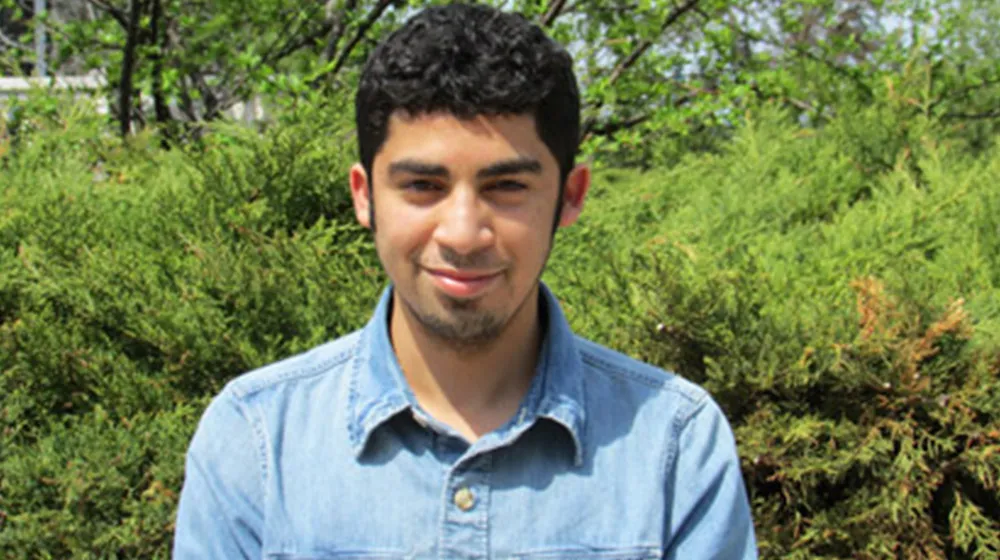 Ali outside in front of a forest backdrop