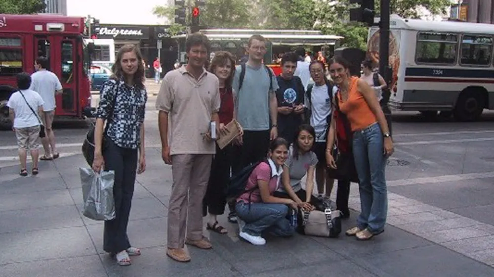 Students gather and pose for a group photo at a bus stop