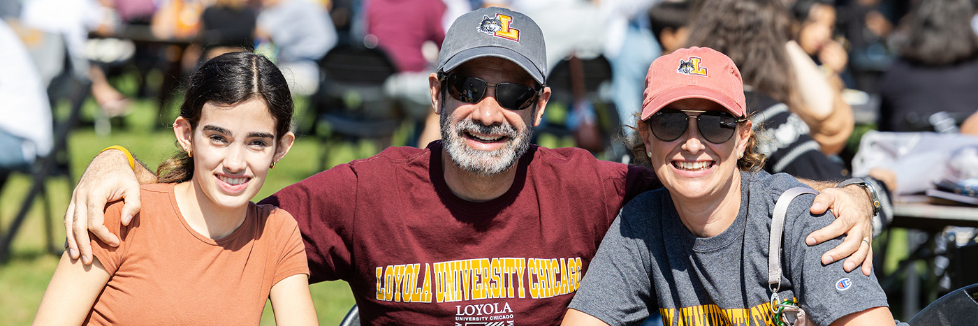 Two parents hug their daughter at Family Weekend at Loyola.