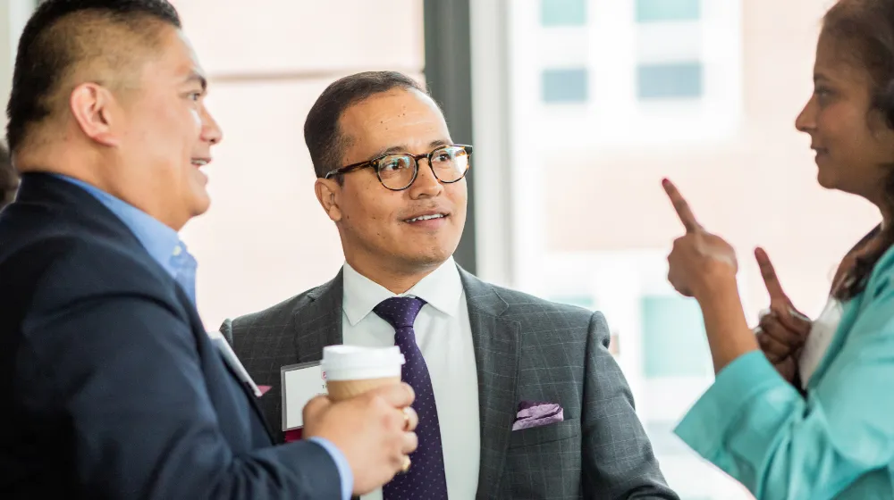Three alumni chat at a Quinlan event