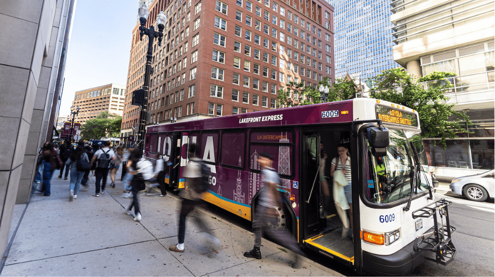 Students walk past and board Loyola’s maroon “Lakefront Express” shuttle bus downtown.