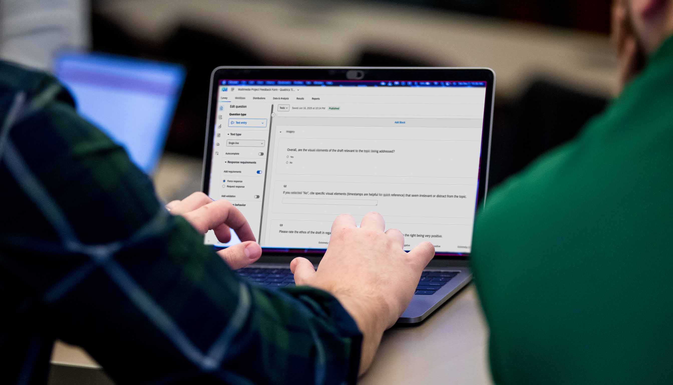 Two individuals working on a Qualtrics survey on a laptop