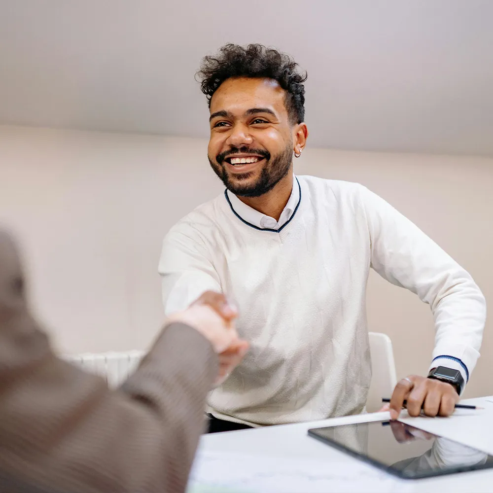 Man in smiling as he shakes someone's hand