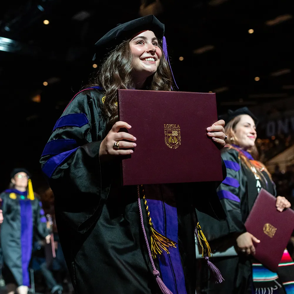 A School of Law graduate walking with her diploma in hand