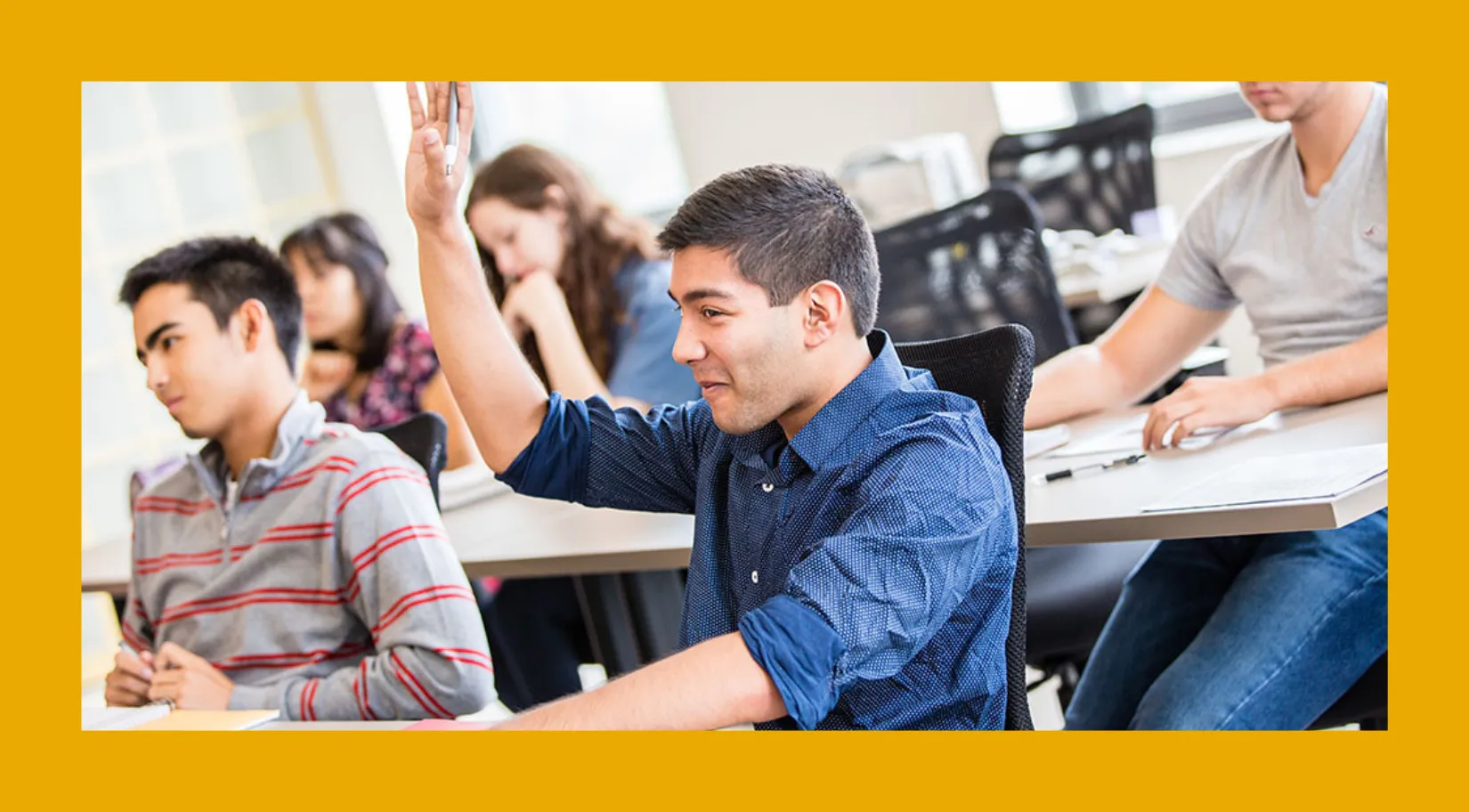 Students in a classroom, with one student raising his hand. 