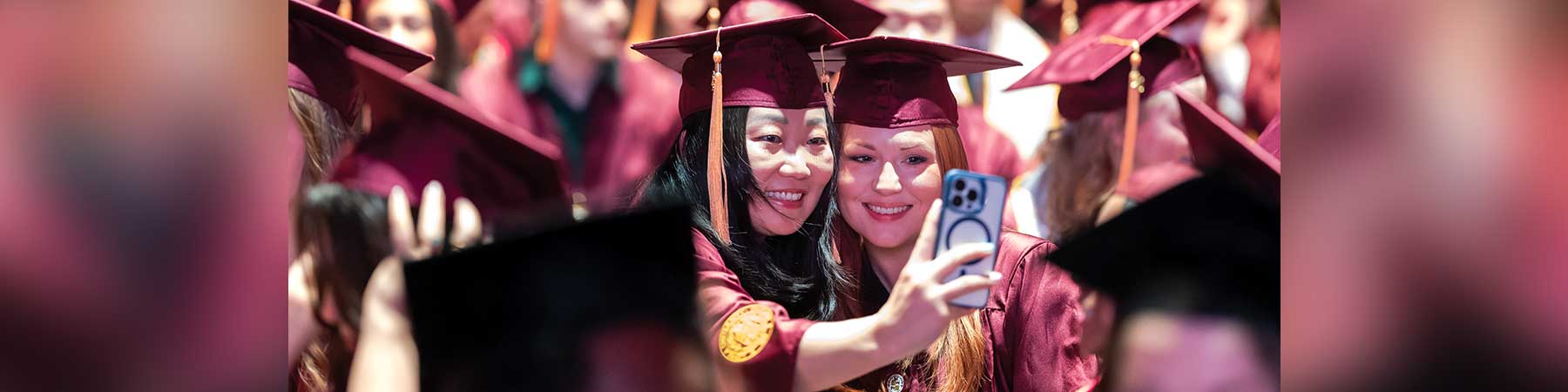 Две студентки-медсестры из Университета Лойолы в Чикаго, делающие селфи вместе на церемонии вручения дипломов