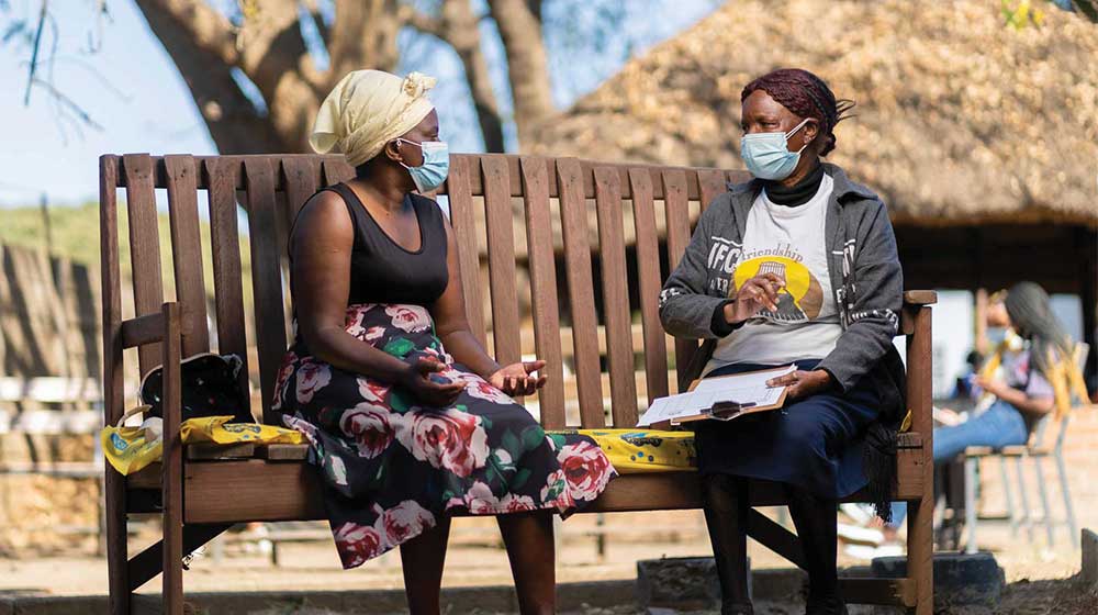 Friendship Bench Ambuya Utano (Community Grandmother) having a problem-solving therapy session on the Friendship Bench in Harare, Zimbabwe.