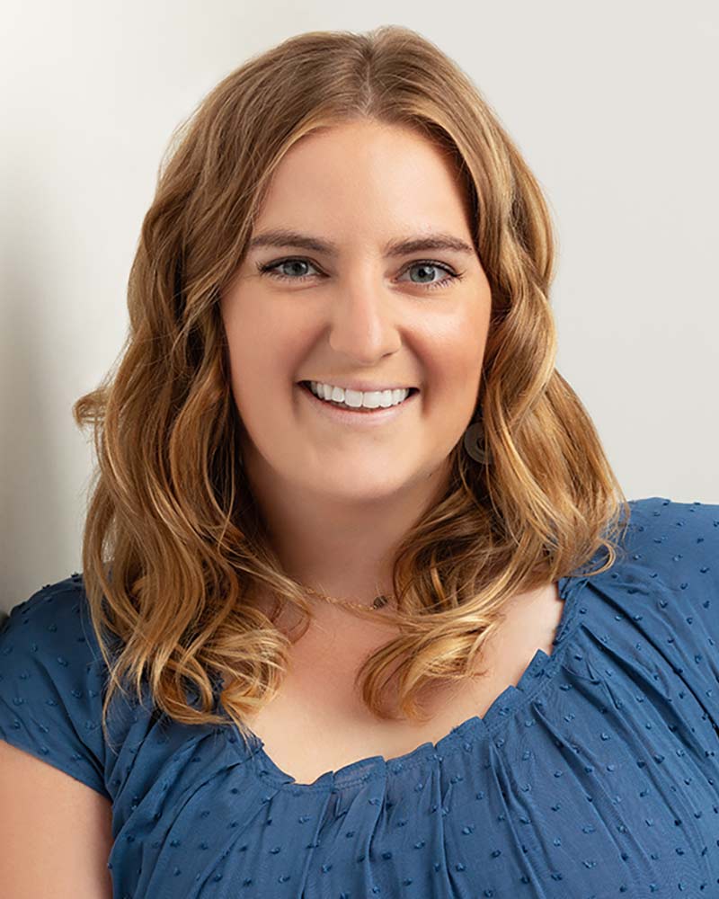 Molly McAdam smiling while she leans against a wall