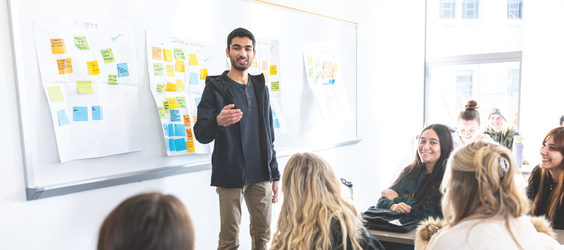 Student in front of whiteboard talking to classmates.