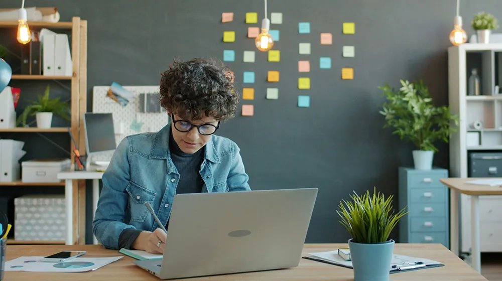 Young professional woman seated at a desk working on laptop