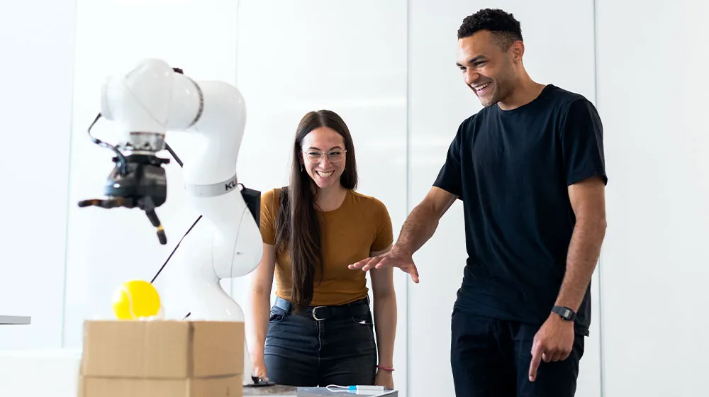 Researchers interact with a robotic arm during a laboratory experiment. Researchers interact with a robotic arm during a laboratory experiment.