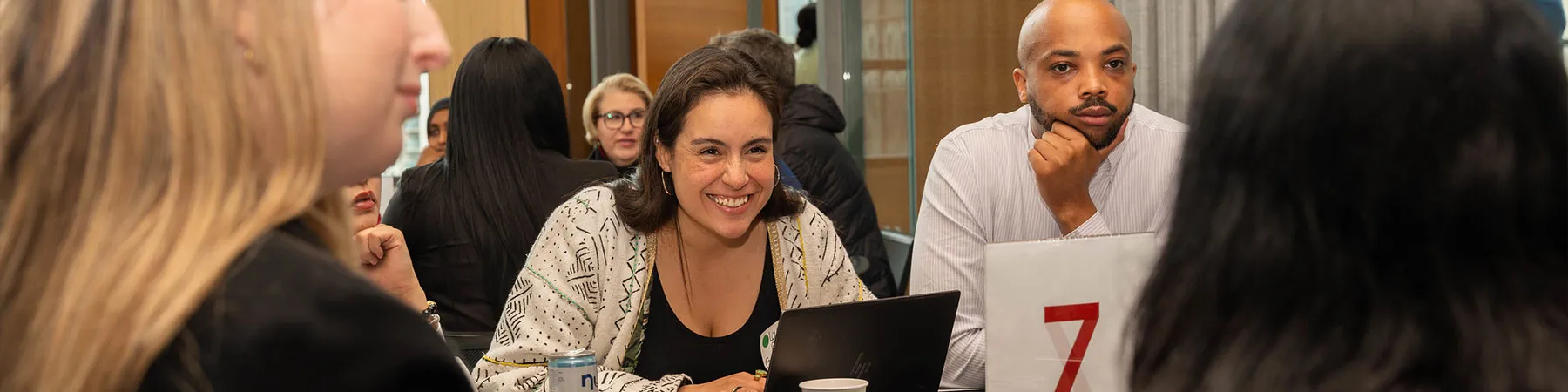 Group of conference goers talking and laughing while seated at a table