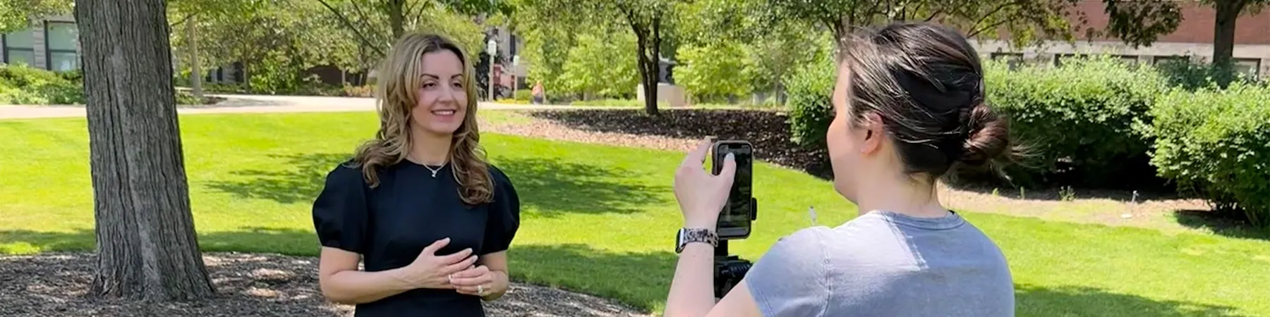 Student filming a woman outside