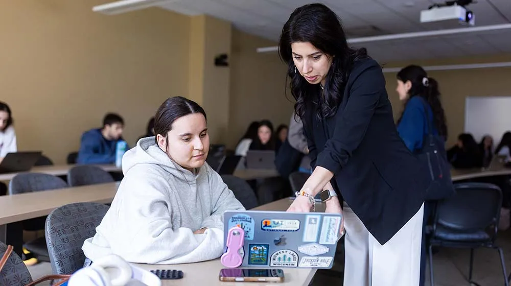 Prof. Azimi and a student discussing while looking at a laptop
