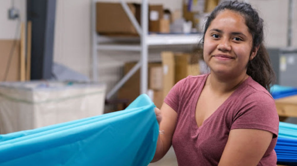 Woman working with a bolt of blue fabric