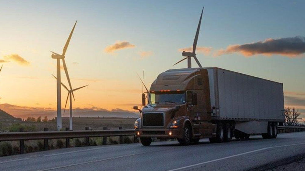 Truck driving on road with wind turbines in background