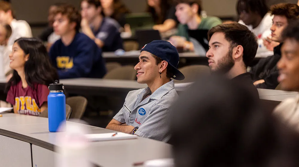 Several students in a classroom listen intently to the instructor.
