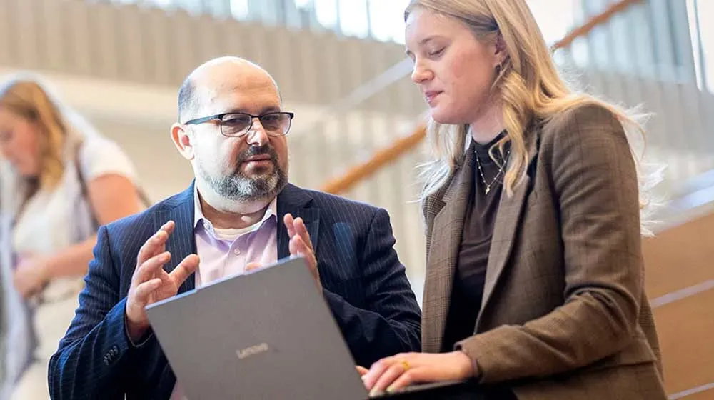 Professor Dinko Bacic and student Angelika Tokarczyk (BBA ’25) discuss over a computer Professor Dinko Bacic and student Angelika Tokarczyk (BBA ’25) discuss over a computer