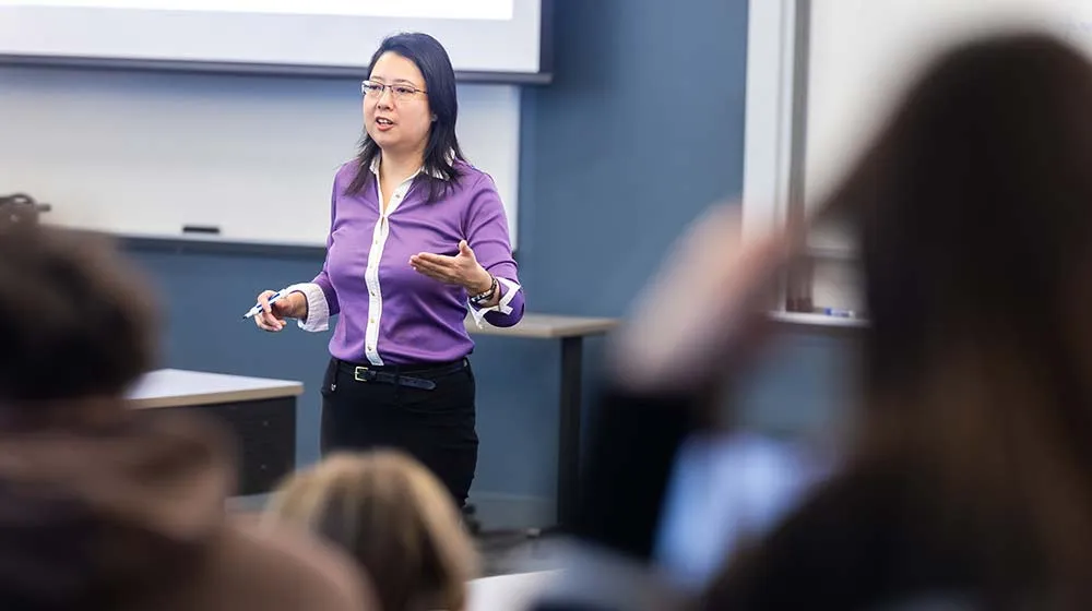 Zongfei Lisa Yang speaks to students as she stands in the center of the classroom teaching.
